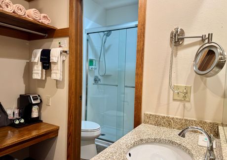 Bathroom with sink, mirror, hairdryer, and view of the toilet.
