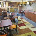 Restaurant interior with tables, chairs, bar, and patterned carpet.