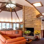 Cozy living room with orange sectional sofa, stone fireplace, and high, angled ceiling.