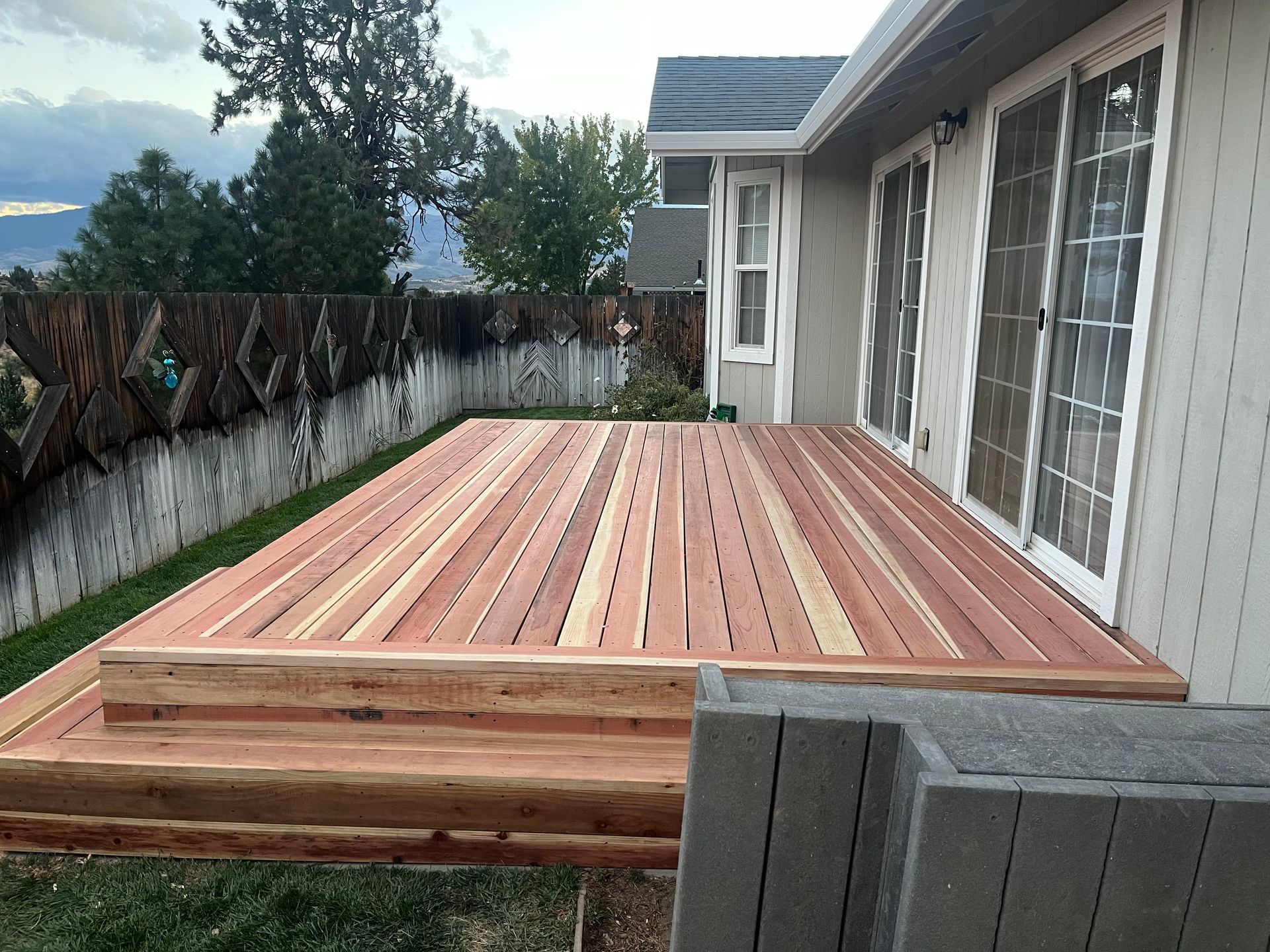 Newly built wooden deck with steps and sliding glass doors.