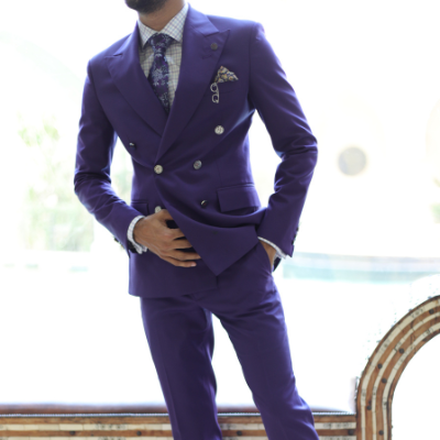 Man in a purple double-breasted suit posing indoors near a bright window