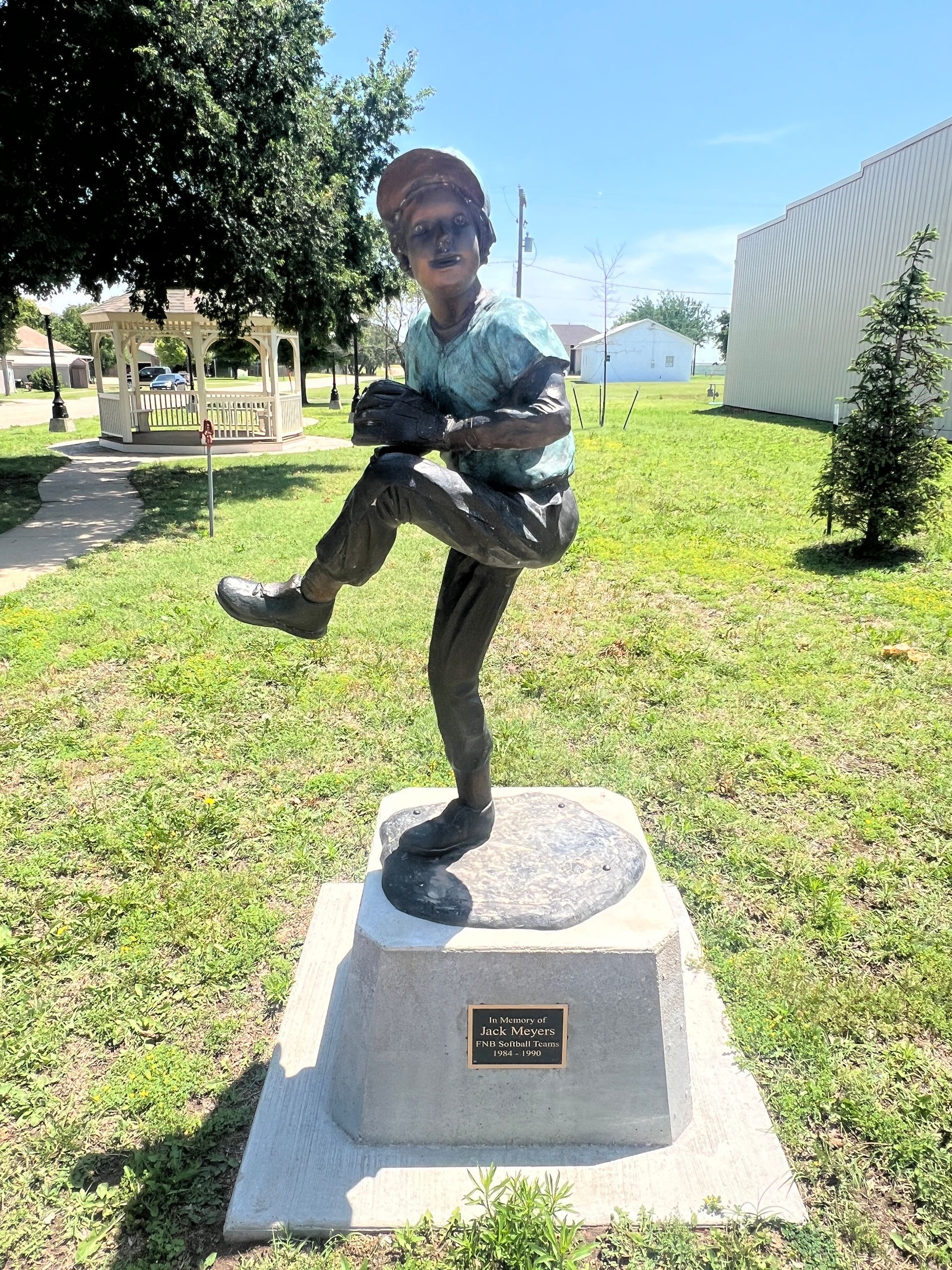 Statue of a child balancing on one leg in a park on a sunny day