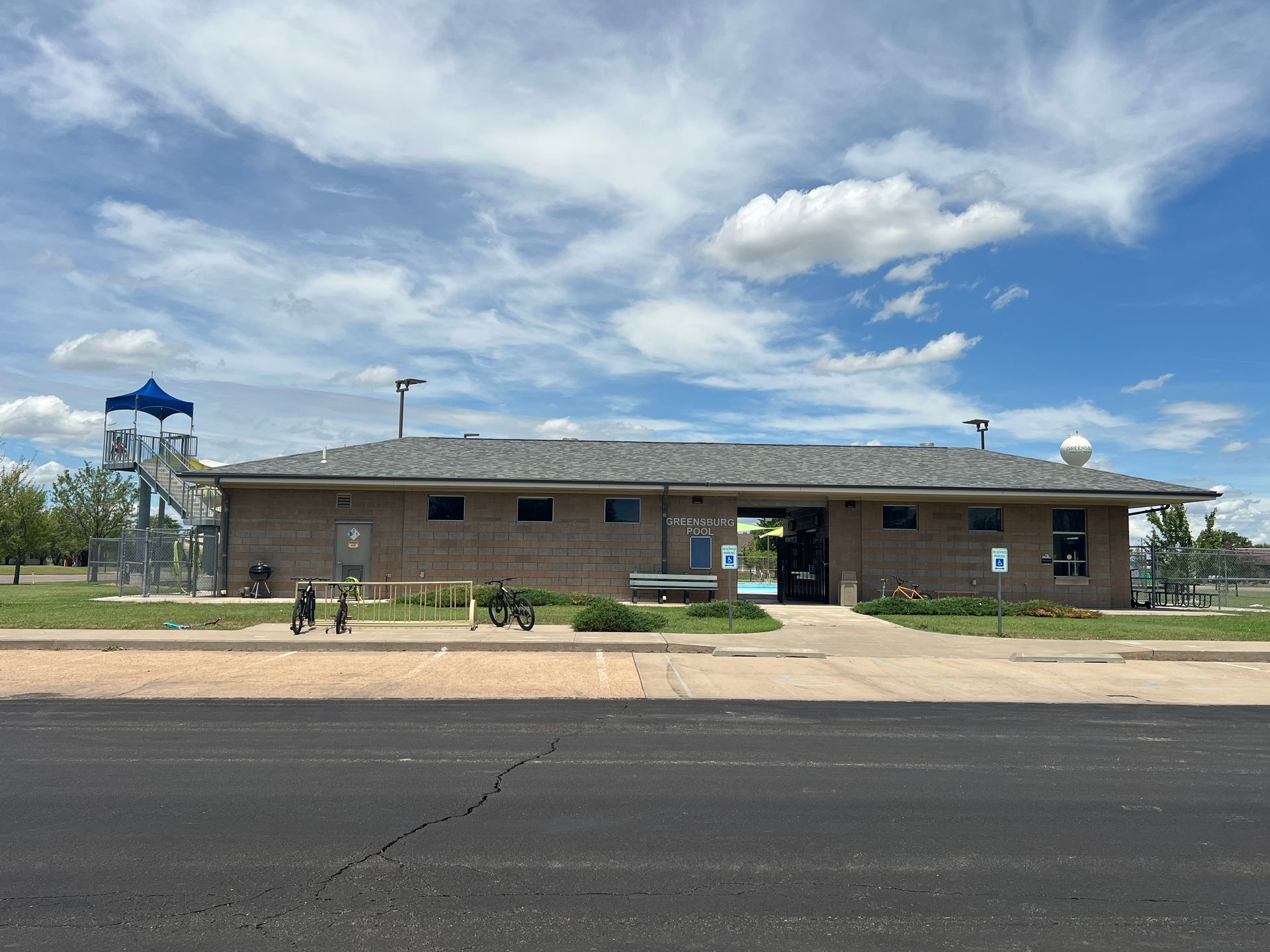Single-story brick building with a blue-roofed playground tower under a cloudy sky.