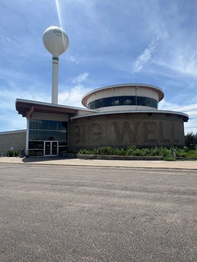 Abandoned brick building with faded “MATTEL” sign and water tower under a blue sky
