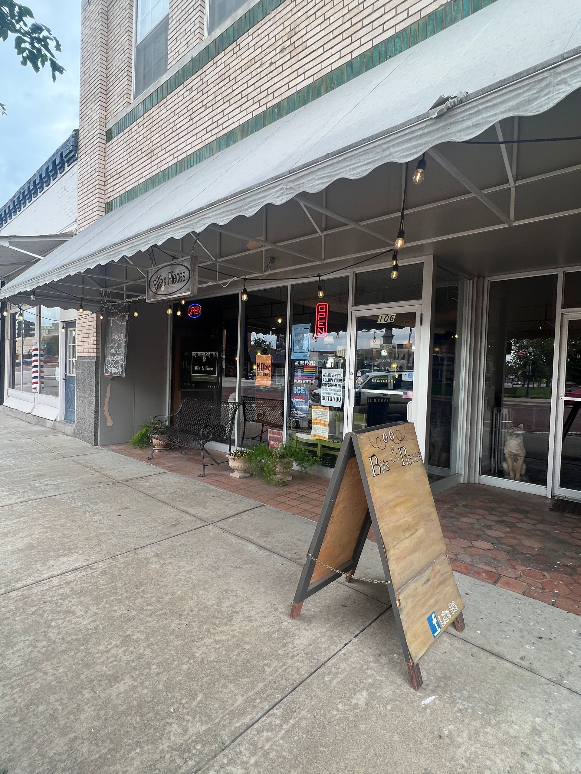 Storefront with awning and sidewalk sandwich board sign on a rainy street