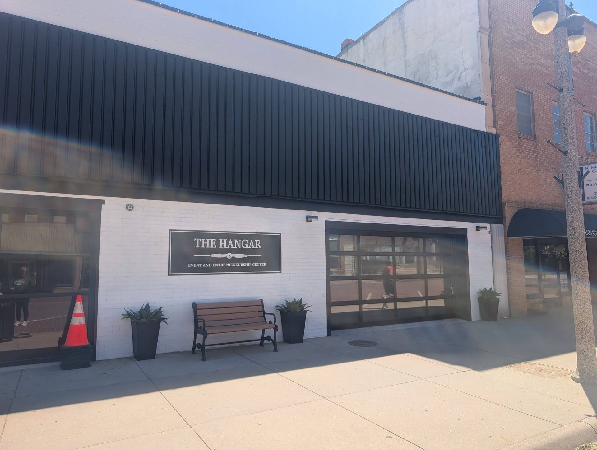Brick storefront with black awning, bench, and sign reading “The Annex” on a sunny street.