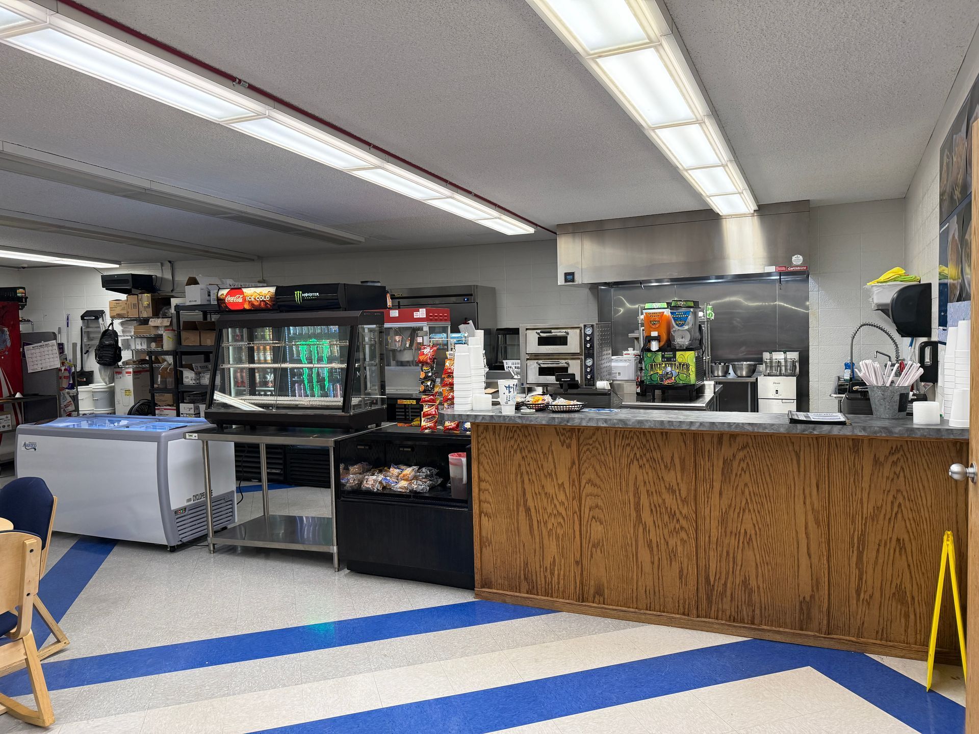 Restaurant counter with display cases, wooden front counter, and fluorescent ceiling lights.