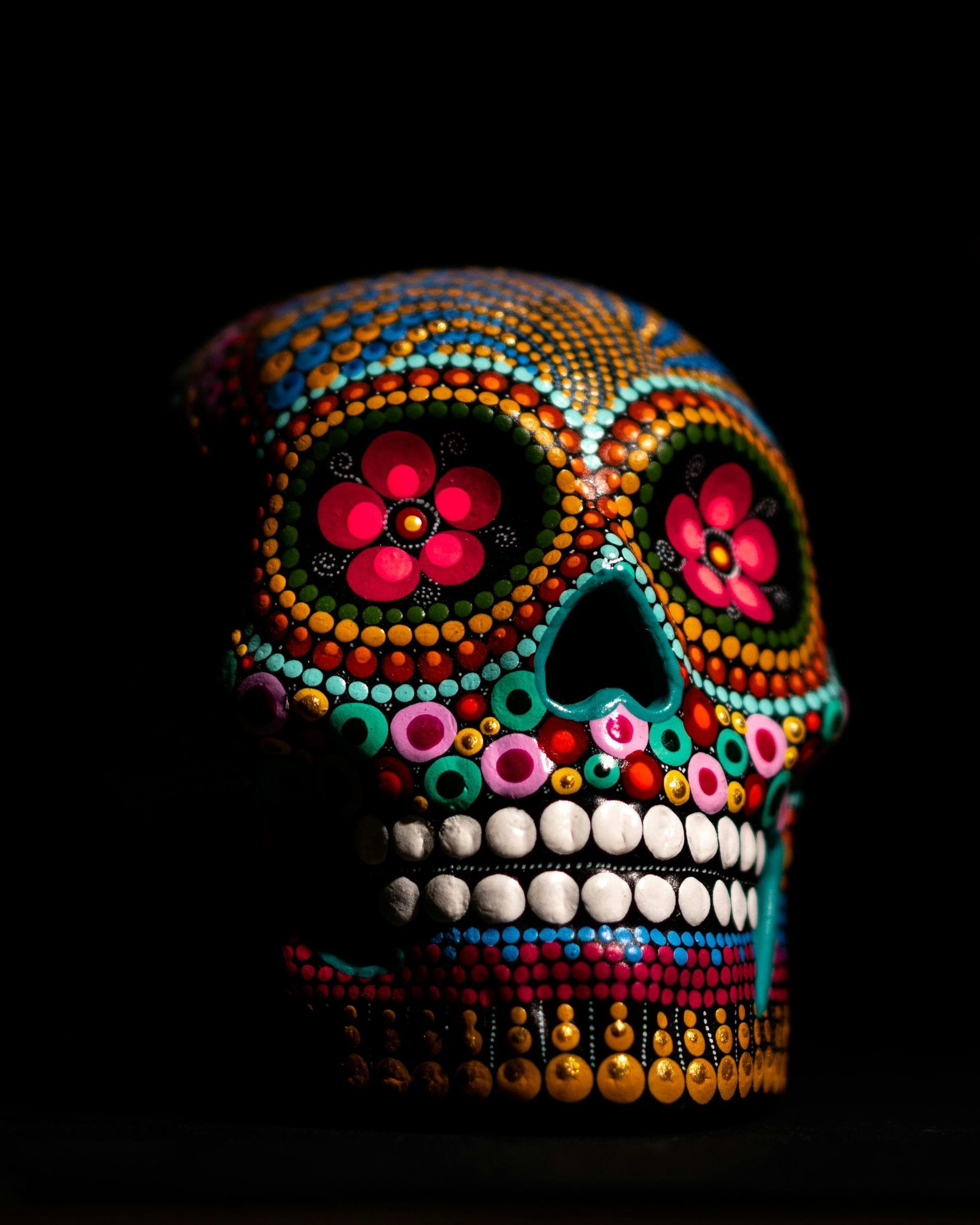 Colorful sugar skull on black background, decorated with floral eyes and bright bead-like patterns