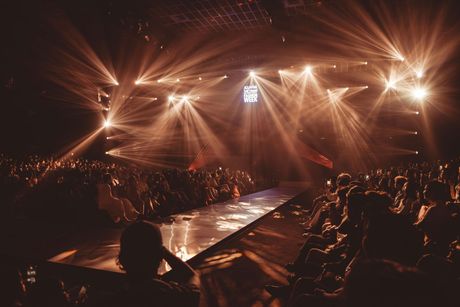 Fashion runway with bright spotlights and seated audience in a dark venue