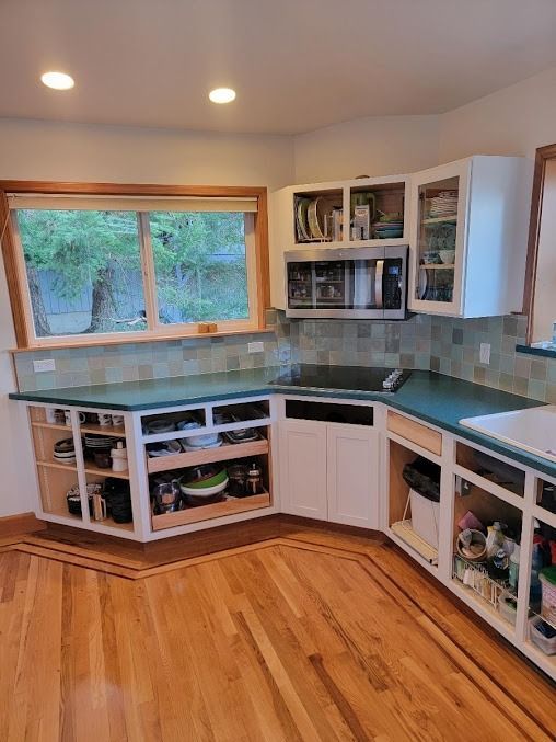 Kitchen remodel in progress, featuring unfinished cabinets, teal countertops, and backsplash.