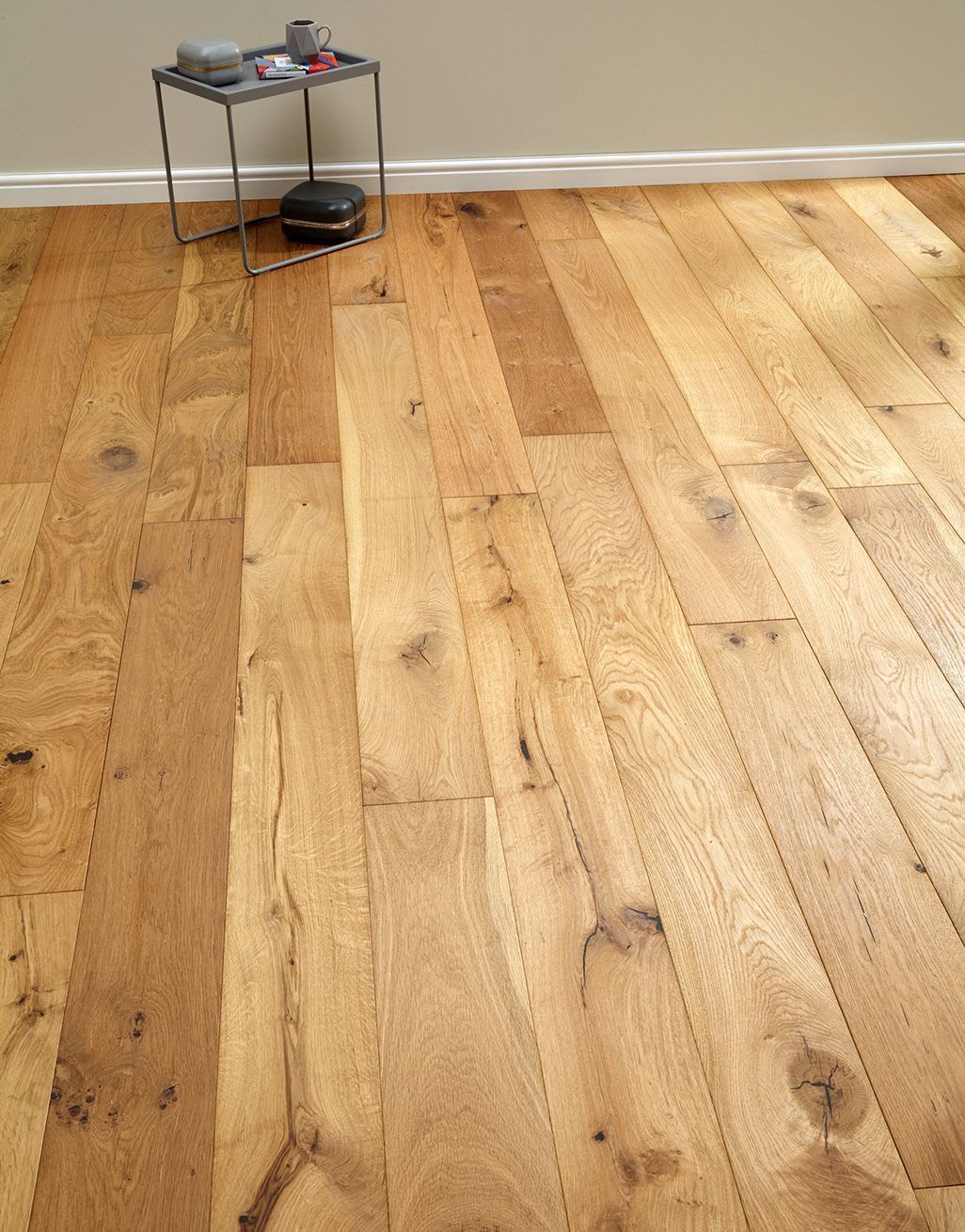 Wooden plank flooring in a room with a small side table against a neutral wall.