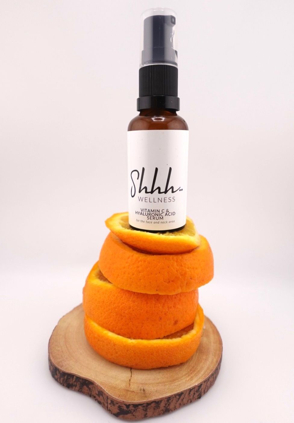 Brown bottle with black pump, atop orange peel stack, on wood slice, with white label reading 
