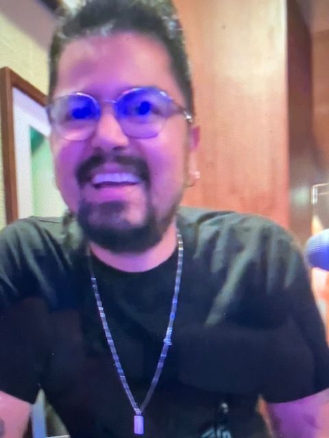 A man wearing glasses and a black shirt is smiling