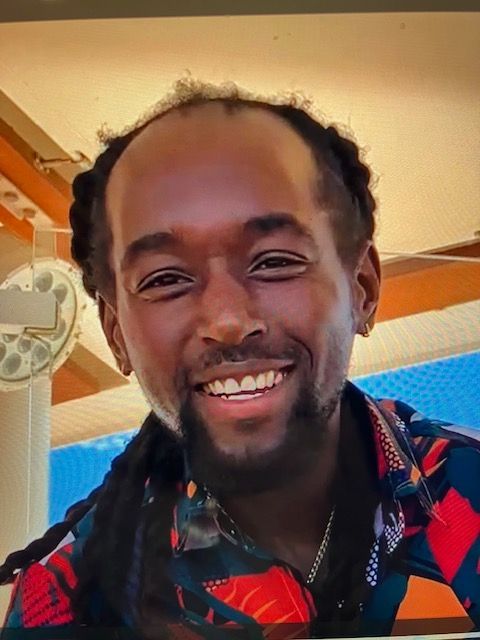 A man with dreadlocks and a beard is smiling for the camera.
