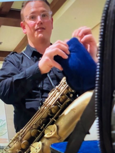 A man in a black shirt is holding a saxophone