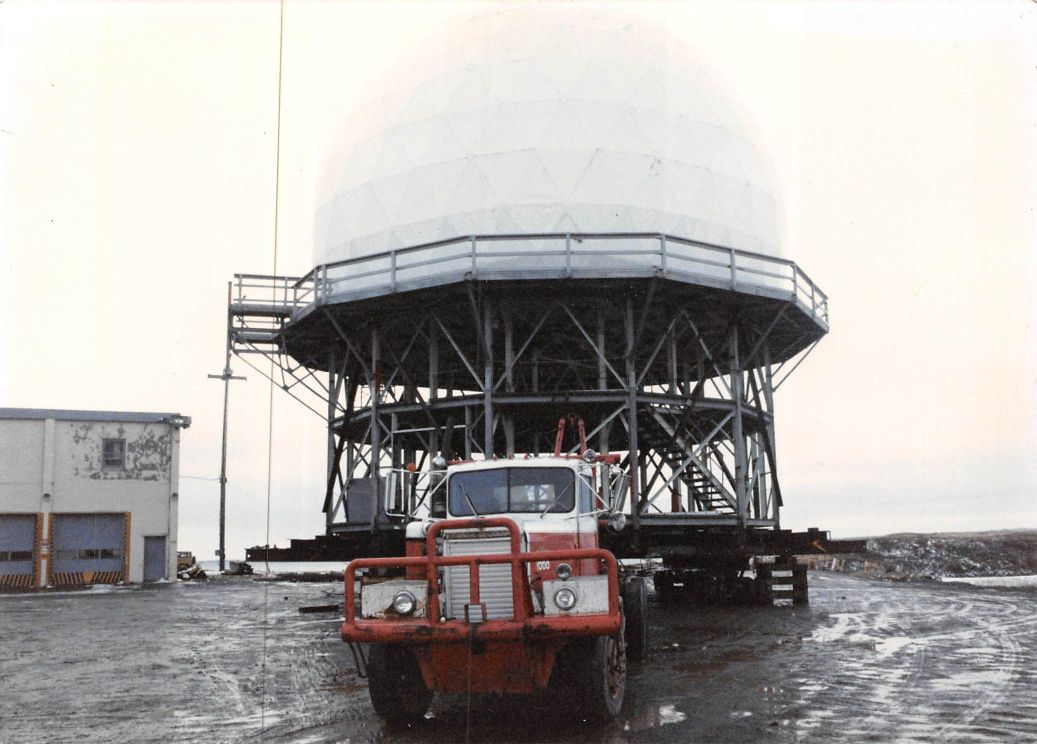 A truck with the number 49 on it is parked in front of a large structure