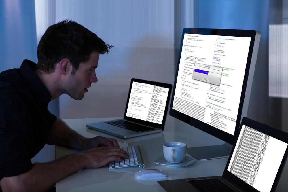 A Man is Typing on a Keyboard in Front of Two Computer Monitors — River City Communications In Wingham, NSW