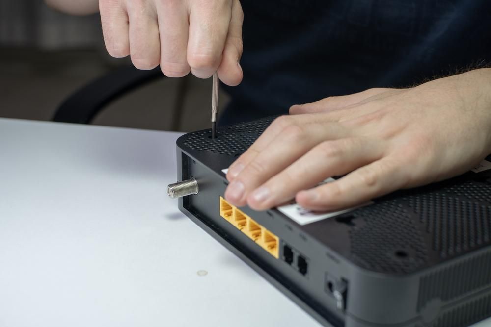 A Person is Fixing a Router With a Screwdriver — River City Communications In Taree, NSW