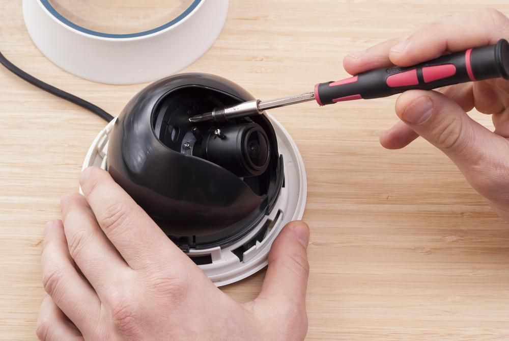 A Person is Fixing a Security Camera With a Screwdriver — River City Communications In Harrington, NSW
