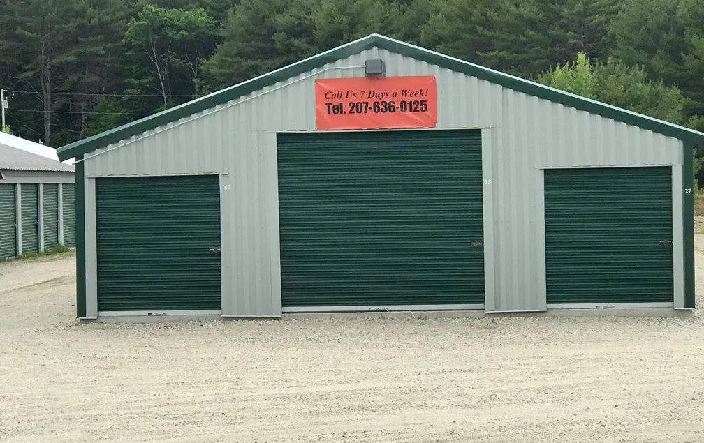 A large metal building with green doors and a phone number on it
