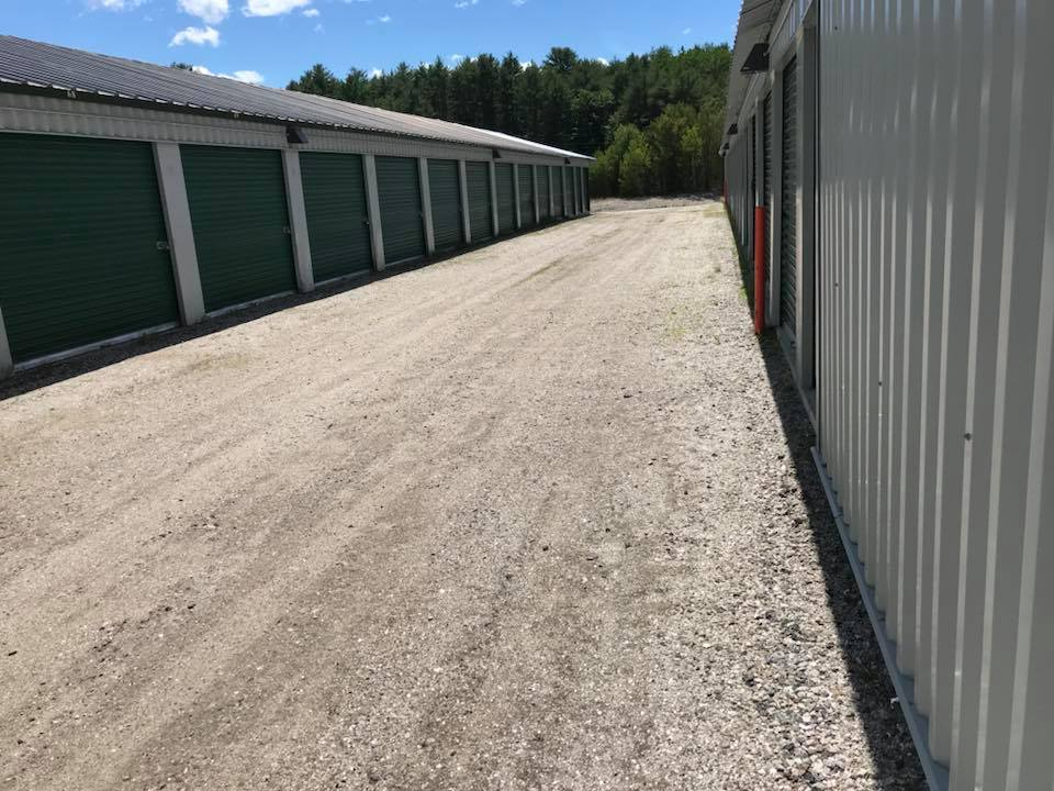 A dirt road leading to a row of storage units.