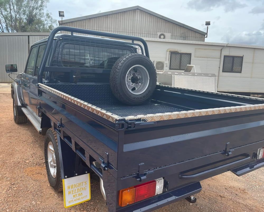 A Blue Truck With a Spare Tire in the Bed is Parked in Front of a Building — Wright's Welding Operations In Ryan, QLD