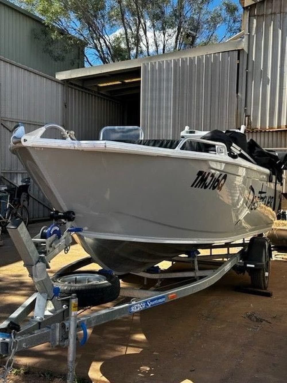 A White Boat is Parked on a Trailer in Front of a Building — Wright's Welding Operations In Ryan, QLD