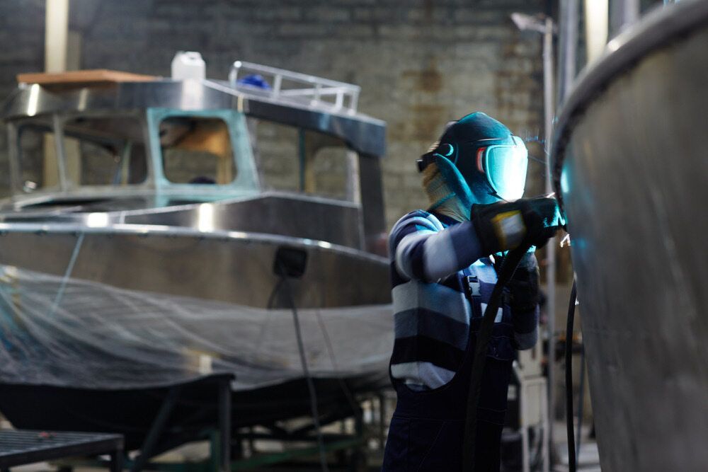 A Man is Welding a Boat in a Factory — Wright's Welding Operations In Ryan, QLD