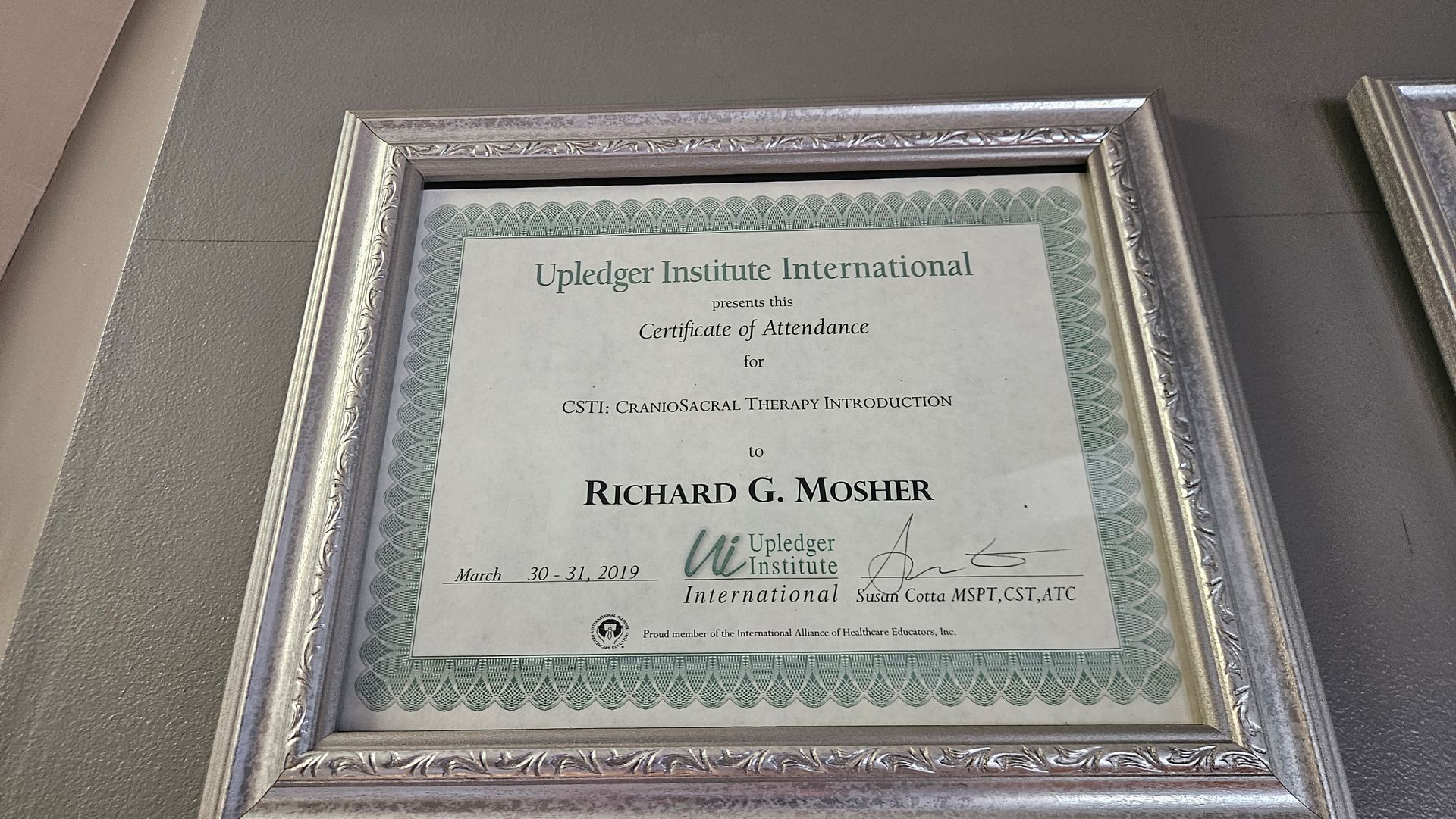 Framed certificate on a gray wall with a green border and the name Richard F. McGah.