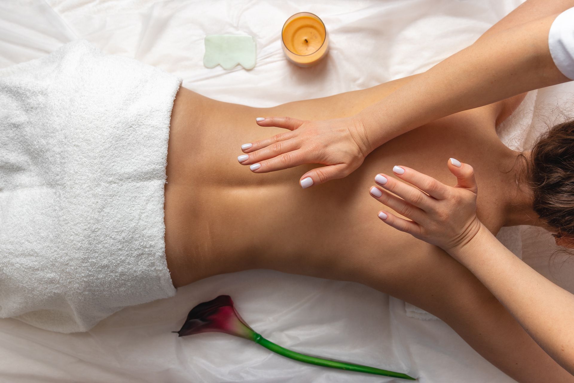 Massage therapist working on a client’s back with cream in a spa setting