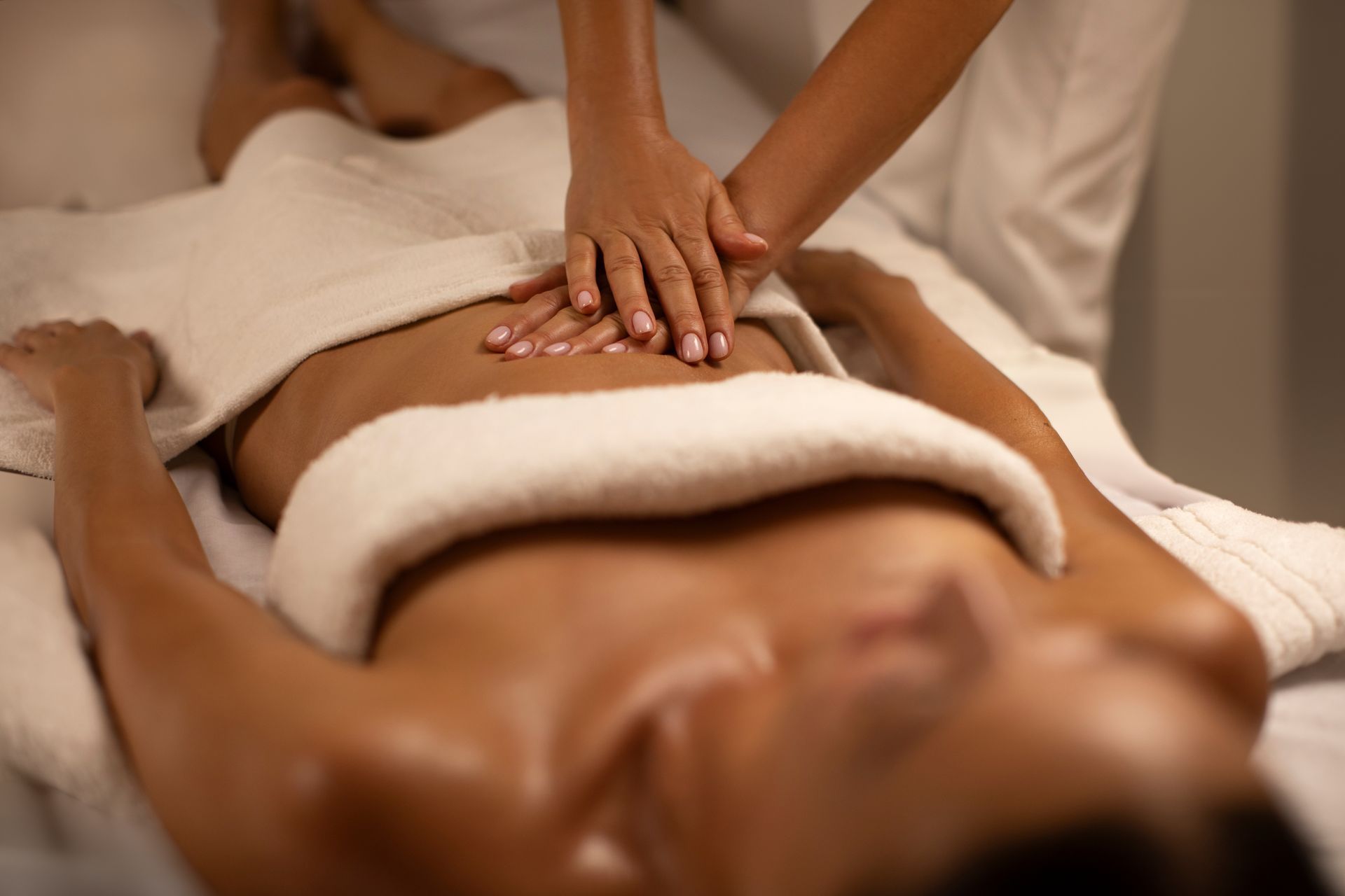 Hands giving a back massage with hot towels in a spa setting