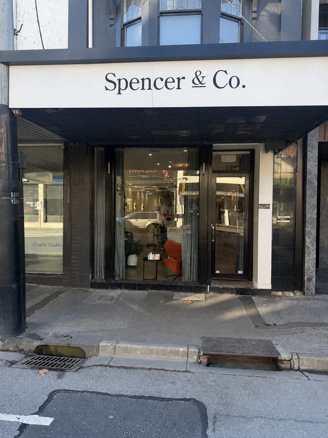 Storefront with sign reading “Spencer & Co.” above glass entrance on a city street