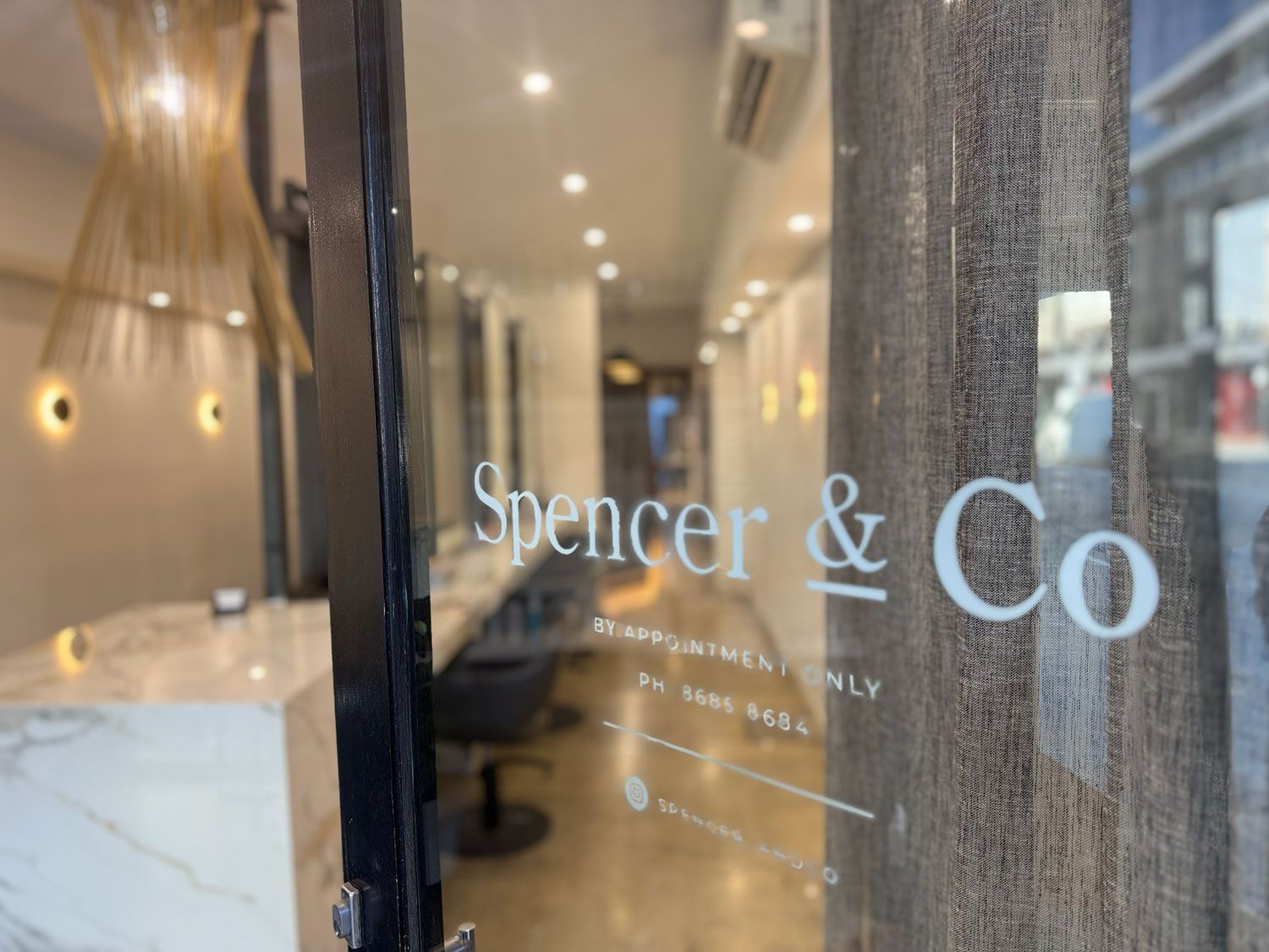 Glass storefront reading “Spencer & Co” with a marble counter visible inside