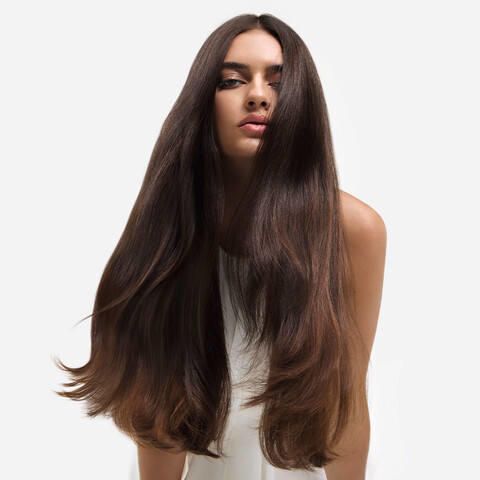 Woman with long, straight dark brown hair against a white background