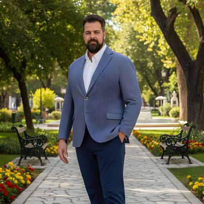 Un uomo con una giacca blu cammina su un sentiero in un giardino, con fiori e alberi alle sue spalle.