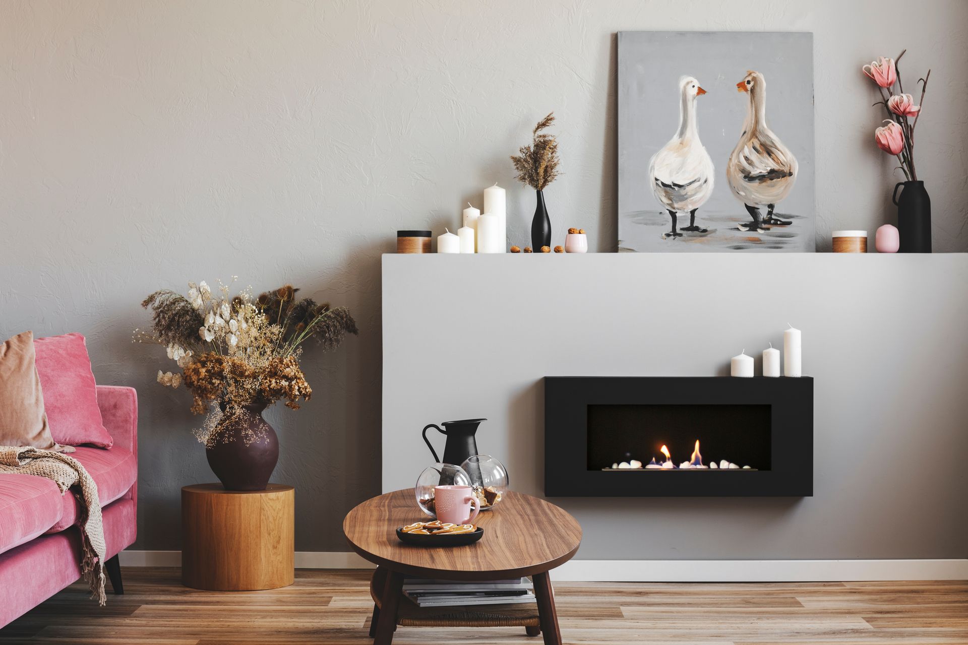 Elegant living room interior with black and grey fireplace, wooden coffee table and pink couch.