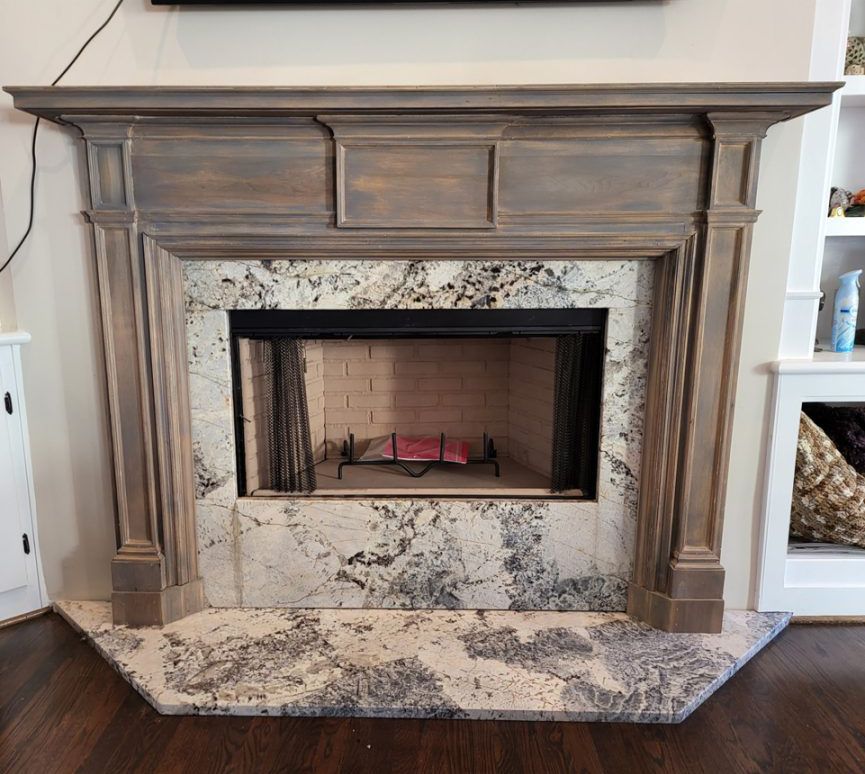 A custom rustic-style fireplace featuring a dark stained wood mantel and granite surround.