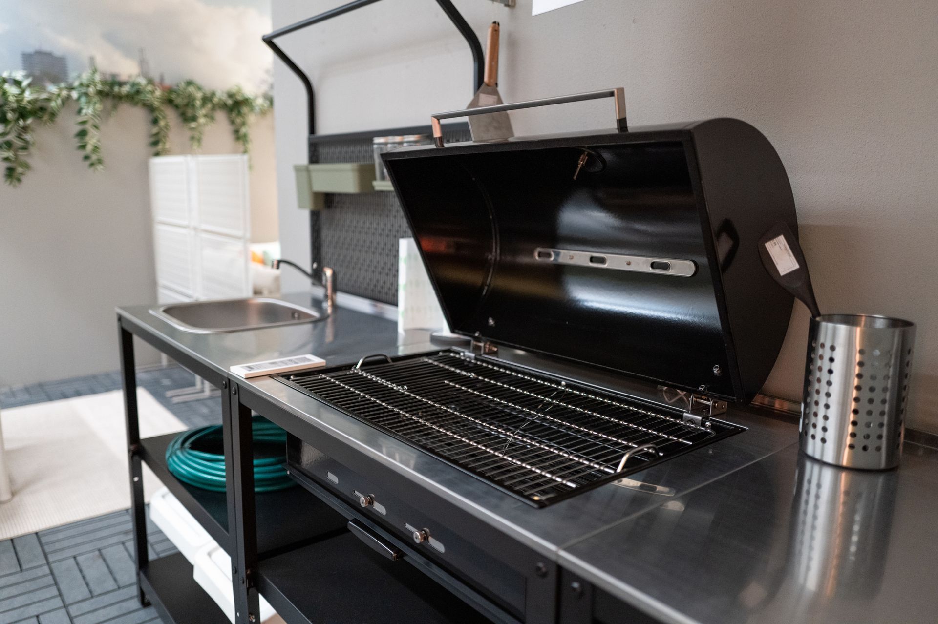 Outdoor grilling station with black grill, stainless steel countertop, and sink.