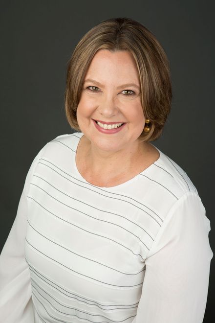 Smiling woman in a white striped top against a dark gray backdrop