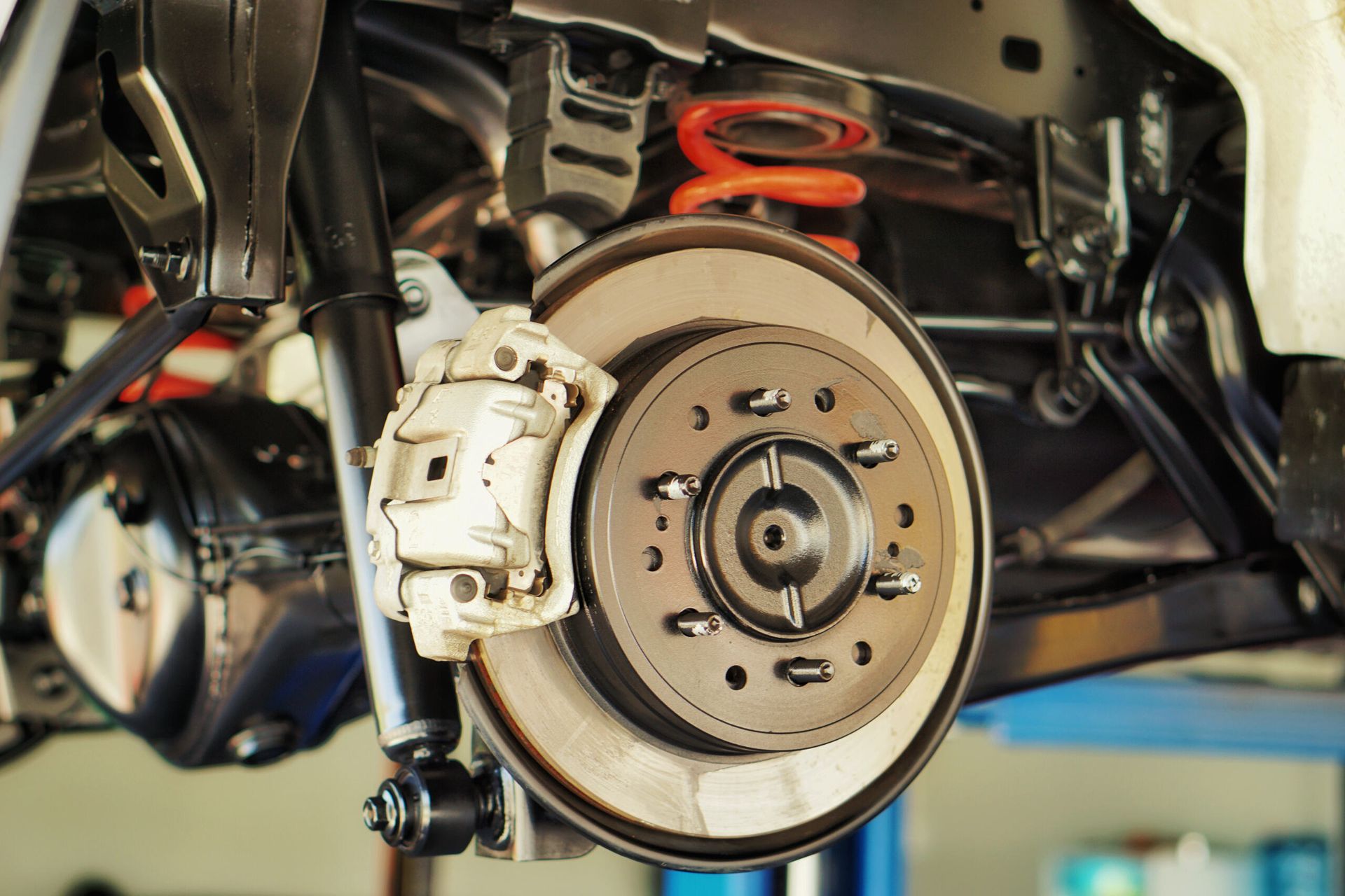A close up of a car 's brake system on a lift. — Protec Mechanical Repairs In Taree, NSW