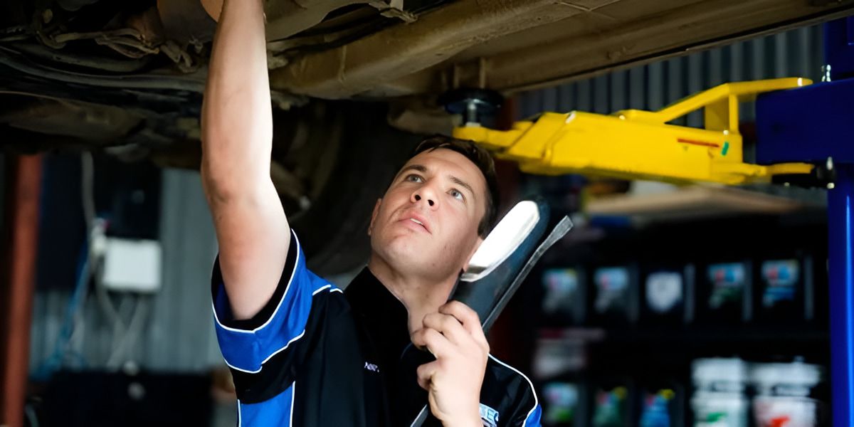 A Man is Working on the Underside of a Car — Protec Mechanical Repairs In Taree, NSW