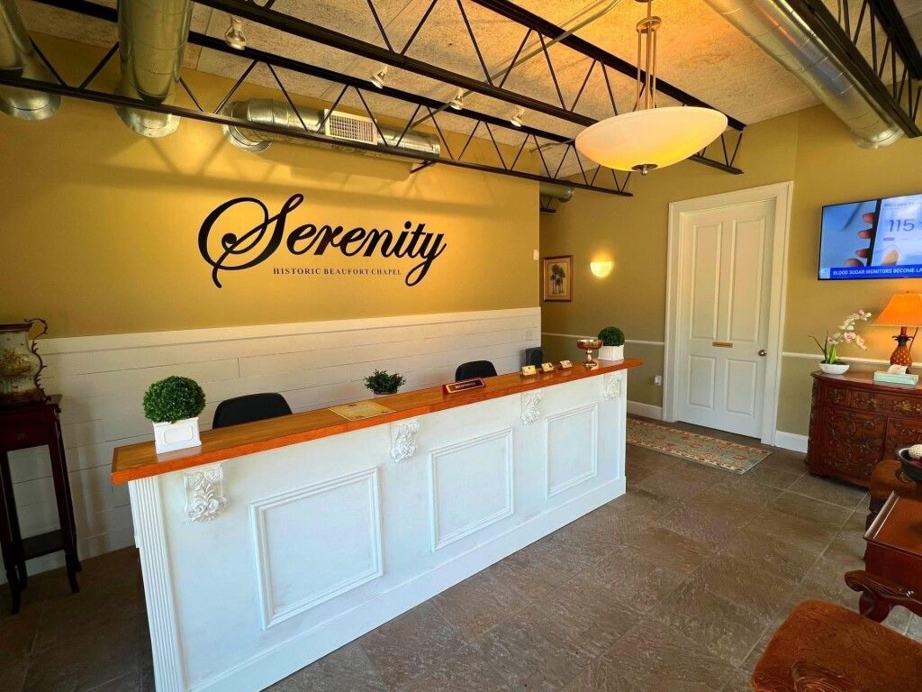 A reception desk in a brightly lit, professional office with tan walls, white wainscoting, and the logo 