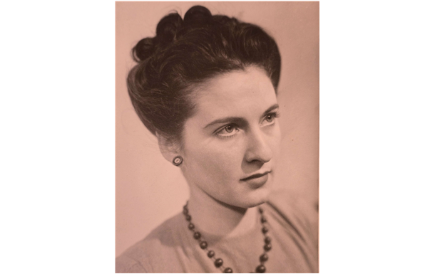 Elderly woman with gray braided hair, gazing at the camera.