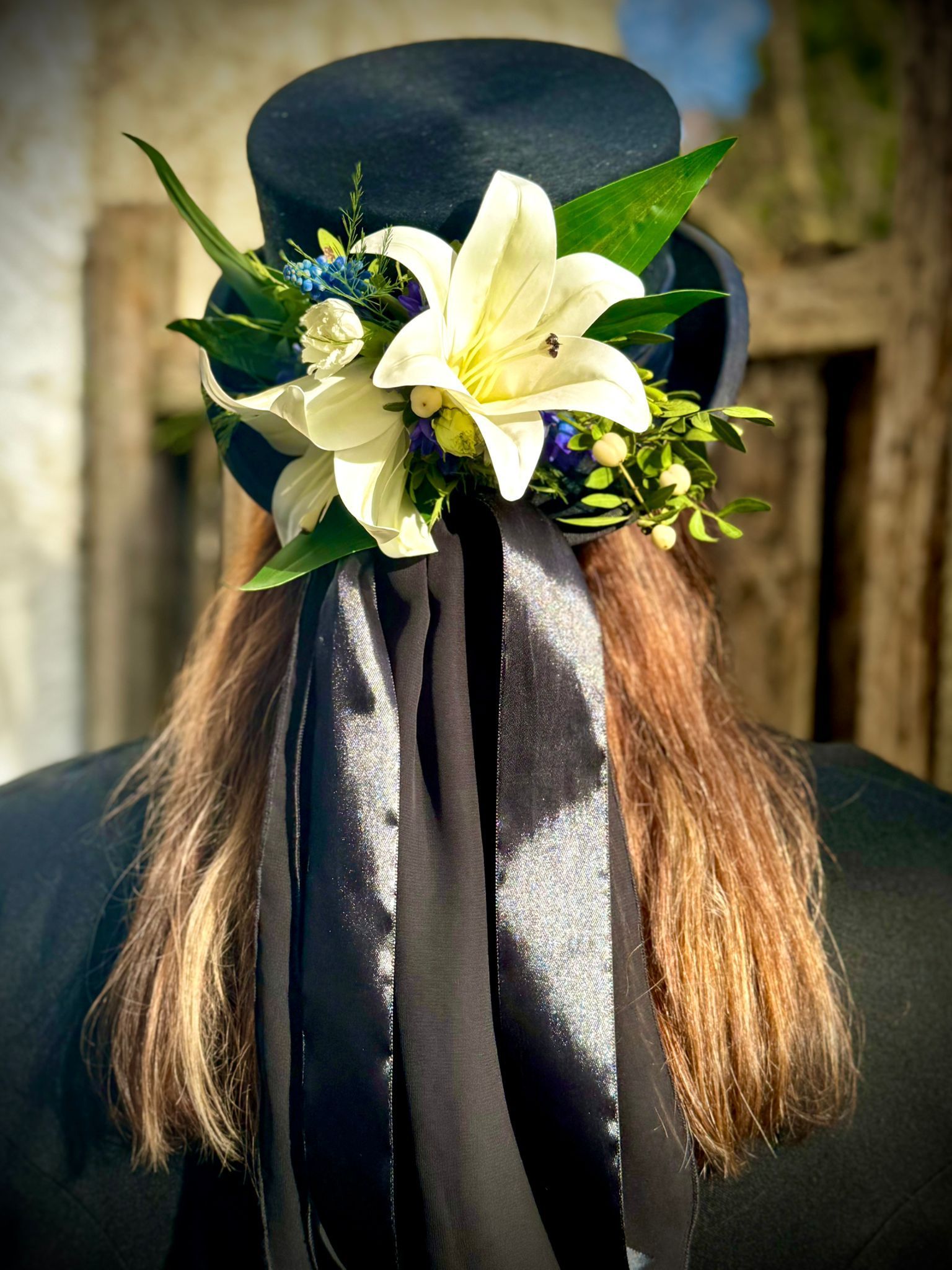A woman wearing a top hat with flowers in her hair