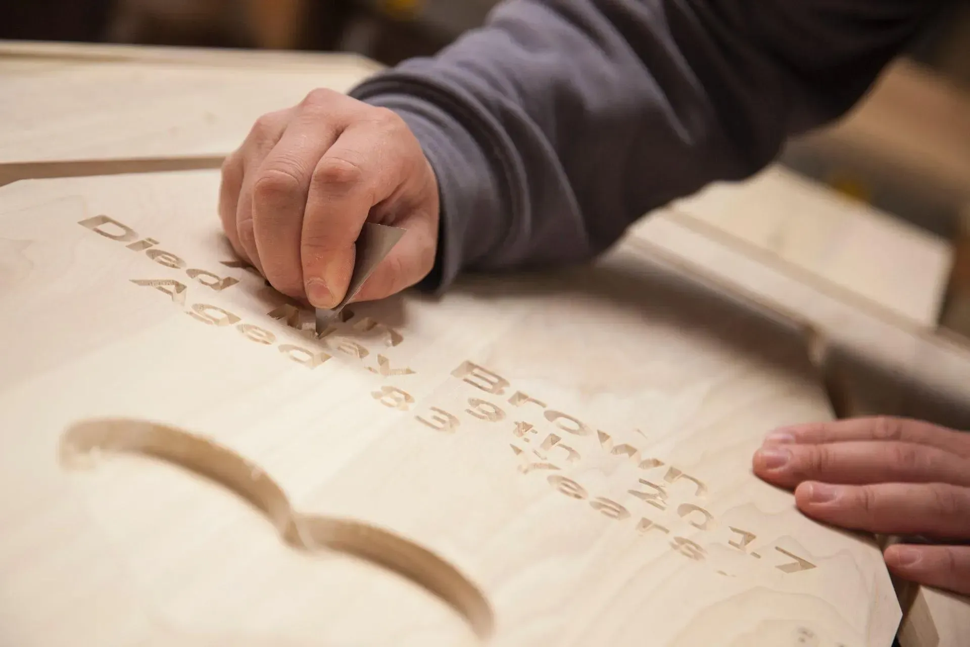 A person is writing on a piece of wood with a marker