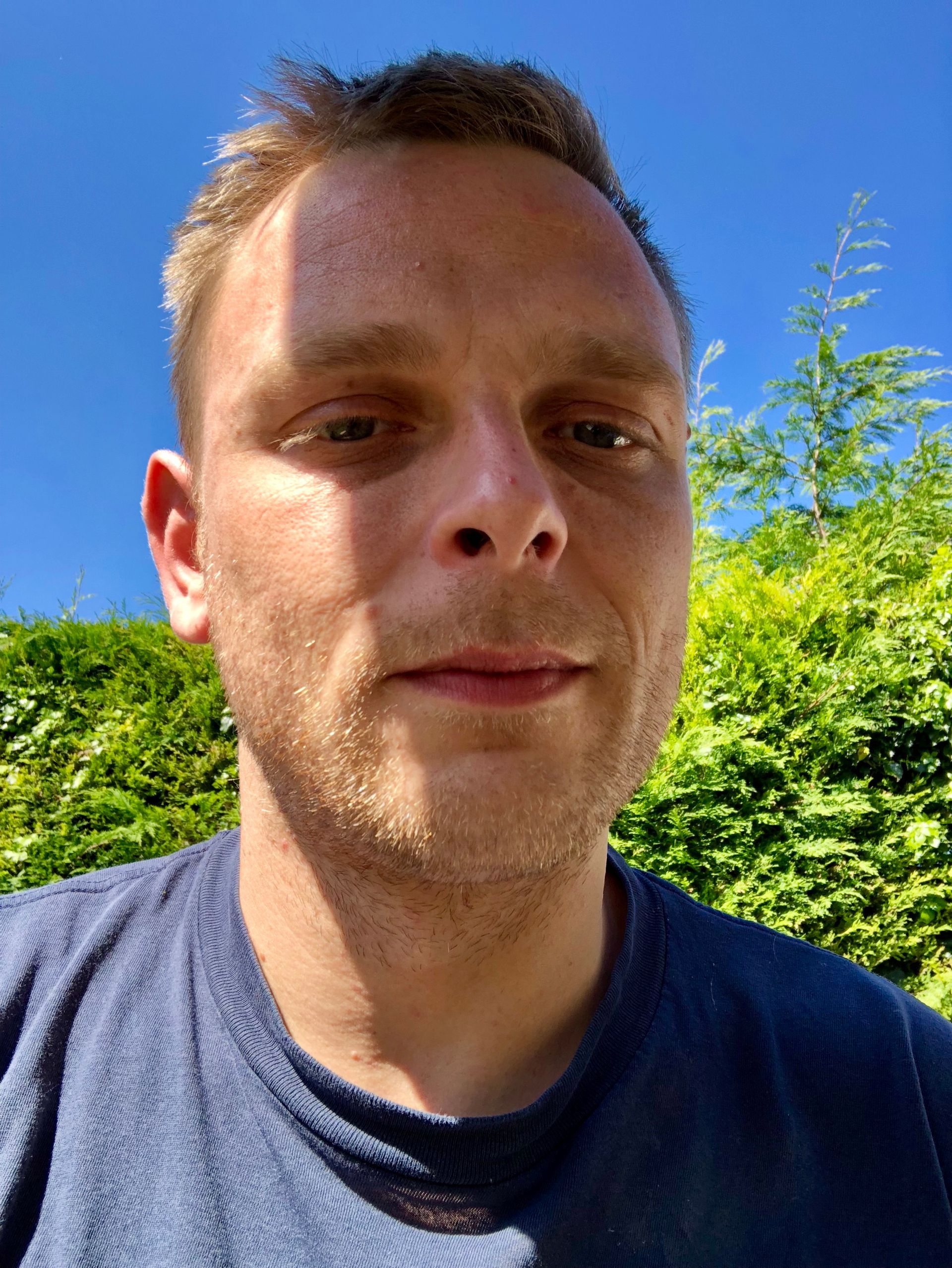 A man in a blue shirt is looking at the camera