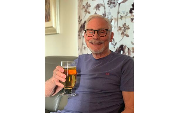 A man is sitting on a couch holding a glass of beer.
