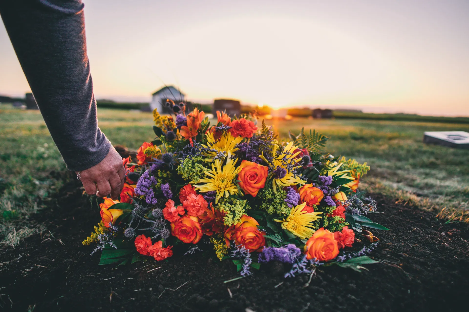 A group of people are standing around a urn at a funeral.