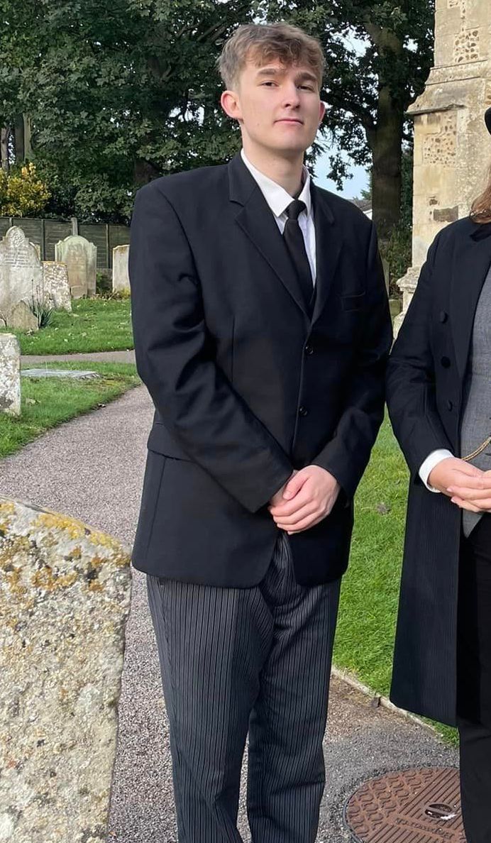 A man in a suit and tie is standing next to a woman in a coat.