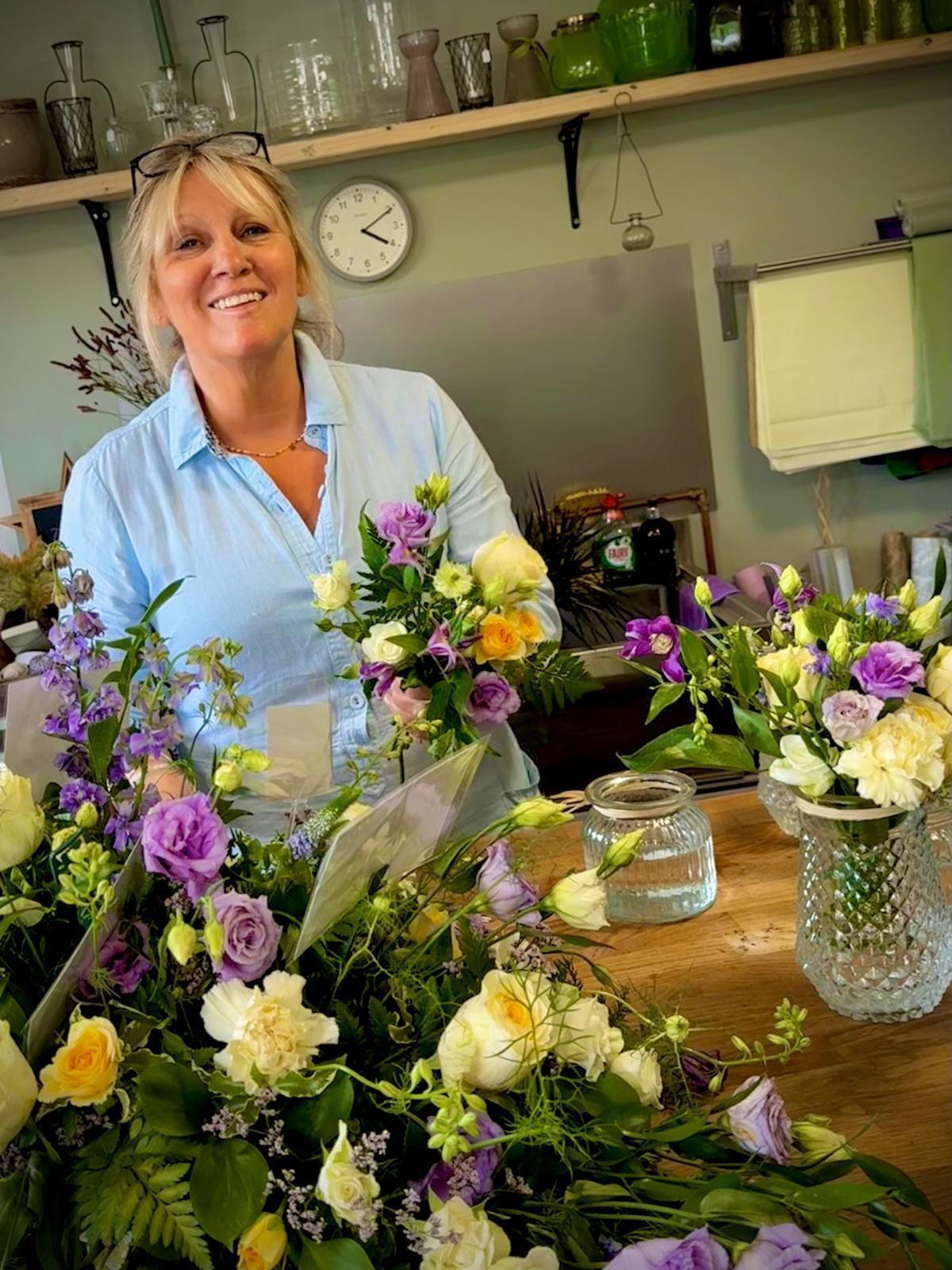 A woman is standing in front of a table full of flowers.
